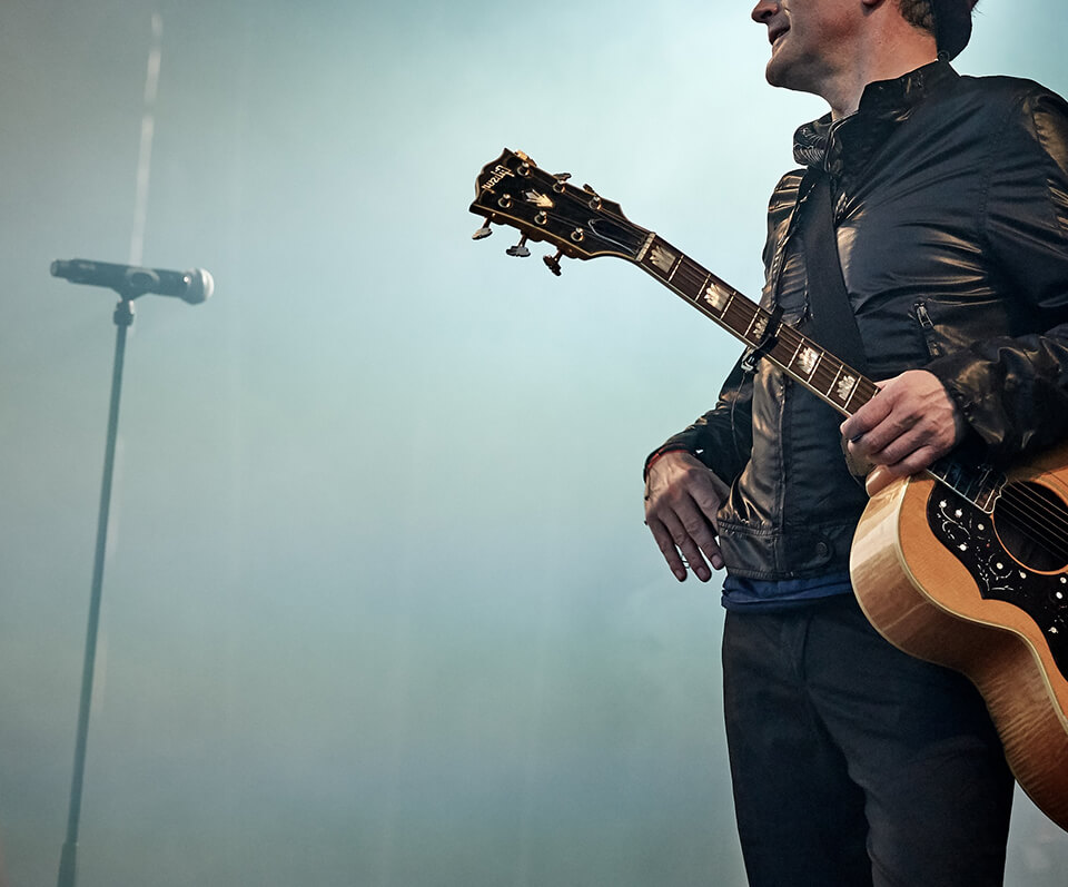 A musician holding a guitar, ready to perform and promote Van Morrison's real quality content and social strategy