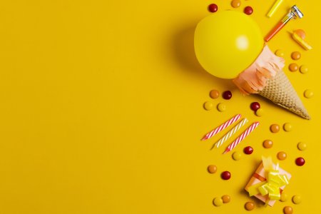 Balloon ice cream, candles and confetti on a yellow background