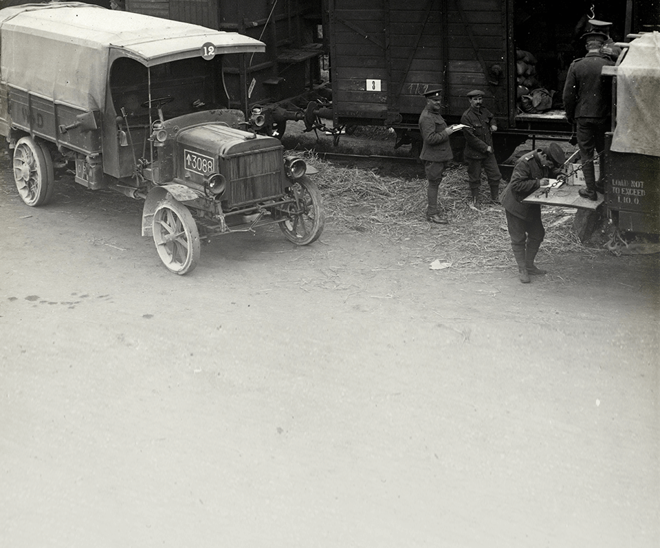 Historic black and white photo of working men in front of an old vehicle
